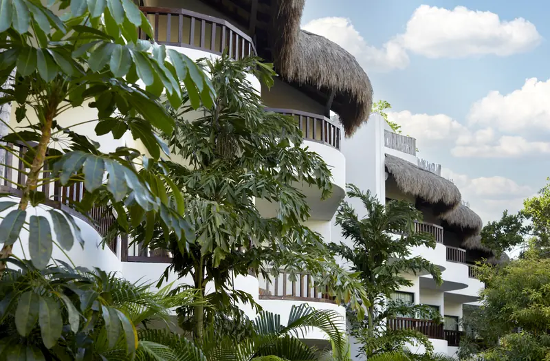 Edificio blanco con techos de palma entre vegetación tropical