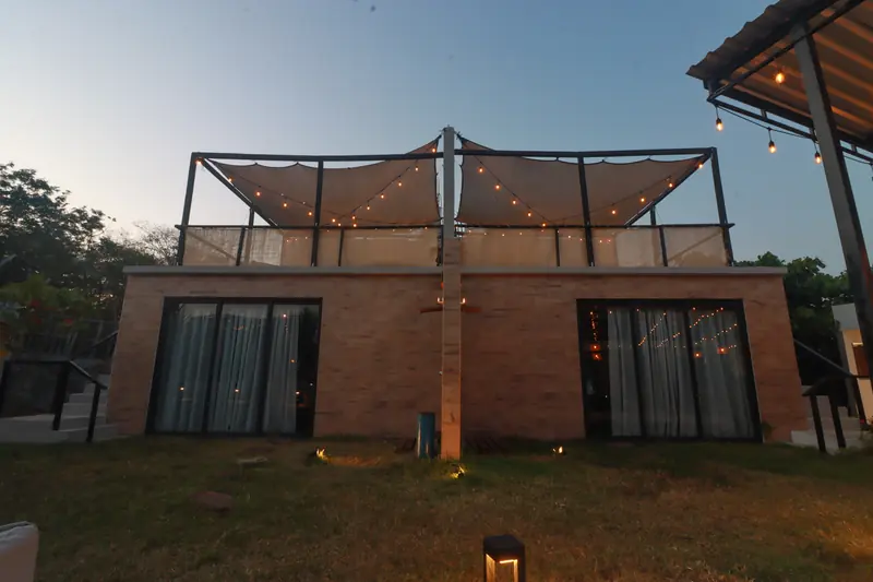 Villa de ladrillo con terraza en azotea y luces colgantes