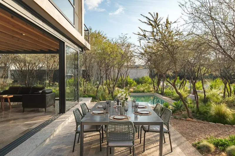 Comedor exterior junto a la alberca y jardín nativo